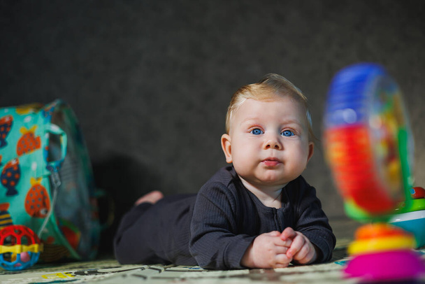 Pieni poika 6 kuukautta makaa matolla ja leikkii leluilla. vauvan itsensä kehittyminen. - Valokuva, kuva