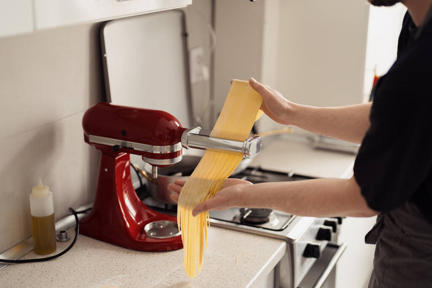 Eine Person, die einen roten Standmixer benutzt, um in der heimischen Küche frischen Nudelteig zuzubereiten. - Foto, Bild