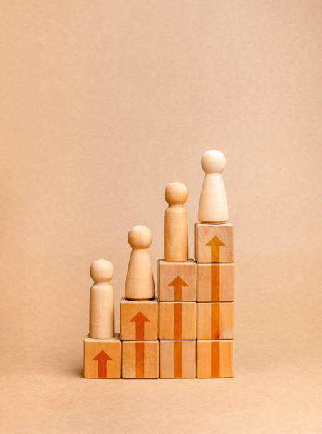 Population growth, increase people, global demography, social and human development concepts. Rising up arrows on wooden cube block graph steps with wooden figures isolated on brown background. - Photo, Image