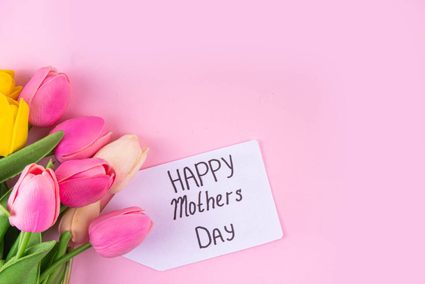 Sfondo della festa della mamma con bouquet di fiori di tulipano, confezione regalo con nastro rosa e tag Happy Mother Day. Sfondo biglietto di auguri, posa piatta per poster, opuscoli, opuscoli, materiale promozionale, sito web - Foto, immagini