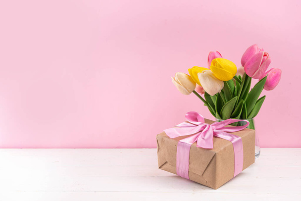 Sfondo della festa della mamma con bouquet di fiori di tulipano, confezione regalo con nastro rosa e tag Happy Mother Day. Sfondo biglietto di auguri, posa piatta per poster, opuscoli, opuscoli, materiale promozionale, sito web - Foto, immagini