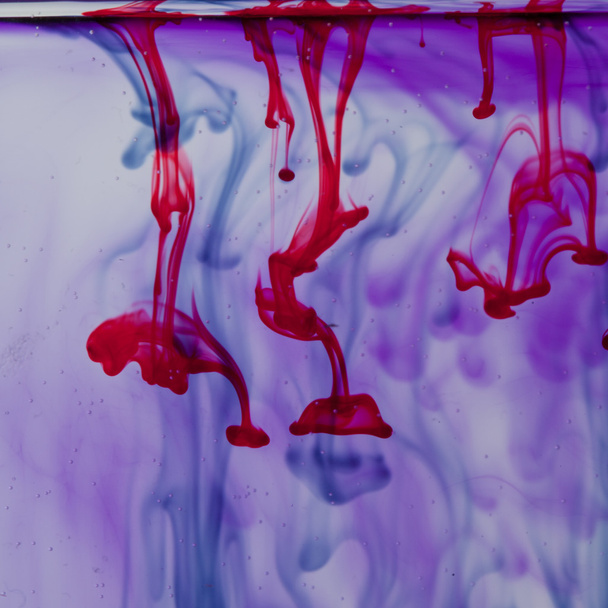 Liquide rouge et violet dans l'eau faisant forme abstraite
 - Photo, image