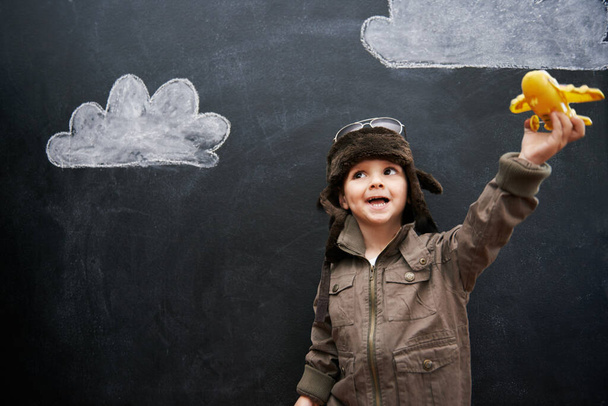 Child, boy and happy by blackboard with plane for creative fun, playing and drawing of clouds for education. Student, kid and confidence with airplane, chalkboard or illustration for knowledge or sky. - Photo, Image