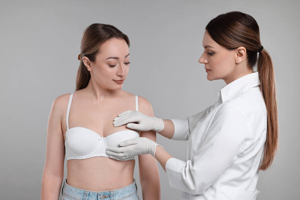 Mammologist checking woman's breast on gray background - Foto, afbeelding