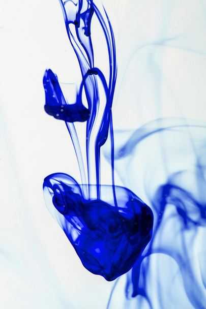 μπλε και ιώδης υγρό στο νερό κάνοντας αφηρημένες φόρμες  - Φωτογραφία, εικόνα