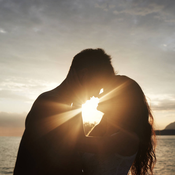Silhouet, koppel en gezicht op zee voor zonsondergang, vakantie of samen reizen in de zomer op lens flare. Man, vrouw en romantiek op zee met schaduw voor verbinding, liefde en avontuur door water buiten. - Foto, afbeelding