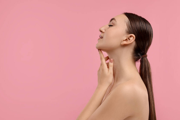 Beautiful woman touching her chin on pink background. Space for text - Photo, image