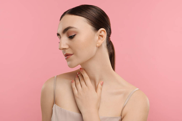 Beautiful woman touching her neck on pink background - Fotoğraf, Görsel