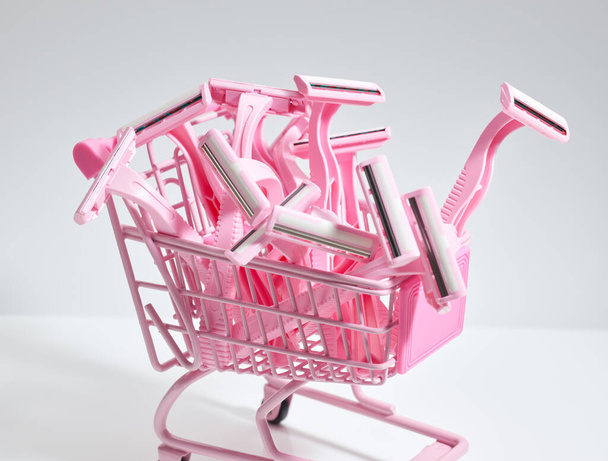 Navajas de afeitar rosadas en el carro de la compra sobre fondo gris - Foto, imagen