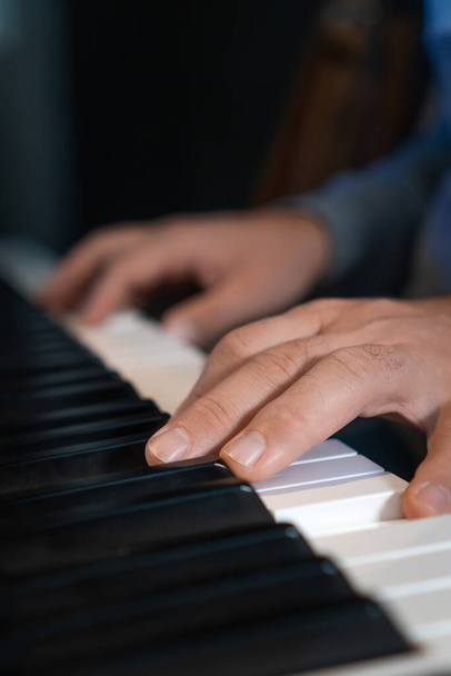 Zbliżenie męskich dłoni grających na elektronicznym pianinie. Wykształcenie muzyczne w szkole muzycznej. Prywatne lekcje muzyki u nauczyciela. Zdjęcie pionowe - Zdjęcie, obraz