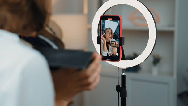 Back view influencer shoot live με smartphpone streaming χρησιμοποιώντας το vlog video review makeup prim social media ή blog. Κορίτσι με φωτισμό στούντιο καλλυντικών για την εμπορική ηχογράφηση σε απευθείας σύνδεση. - Φωτογραφία, εικόνα