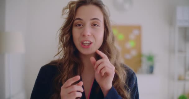 Slow motion portret van mooie jonge vrouwelijke brunette influencer praten in de woonkamer thuis - Video