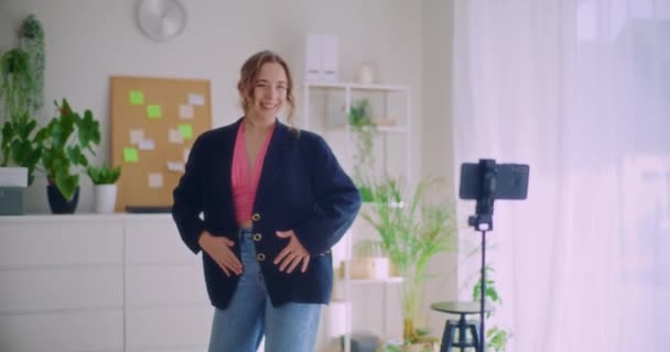 Slow motion shot της όμορφης νεαρής γυναίκας influencer καταγραφή βίντεο χορού μέσω κινητού τηλεφώνου στο τρίποδο στο σπίτι - Πλάνα, βίντεο