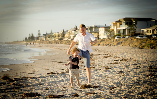 feliz padre jugando en la playa con su pequeño hijo corriendo excitado con los pies descalzos en la arena y el agua
 - Foto, imagen