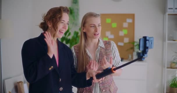 Медленная съемка счастливых молодых подруг, работающих вместе через смартфон на моноподе дома - Кадры, видео