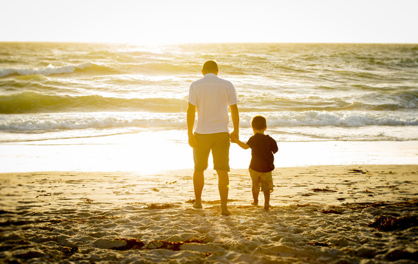 幸せな父の持株一緒に裸足でビーチを歩く幼い息子の手を握って - 写真・画像