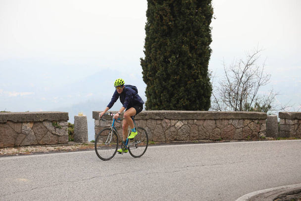 νεαρός ποδηλάτης πεντάλ ανηφόρα για αγωνιστικά ποδήλατο κατά τη διάρκεια του αγώνα ποδηλασίας βουνού - Φωτογραφία, εικόνα