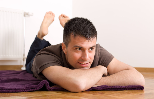 Mies makaa vatsallaan lattialla
 - Valokuva, kuva