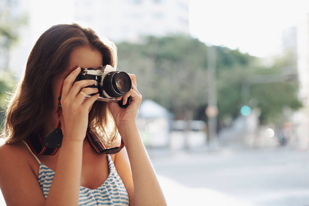 Woman, photography and city street with camera for photo, memory or capturing outdoor moment. Female person, tourist or photographer taking picture with lens for sightseeing or travel in urban town. - Photo, Image