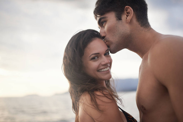 Portret, uśmiech i pocałunek pary w oceanie na wakacjach, wakacjach lub wspólnej podróży o zachodzie słońca. Twarz, mężczyzna i szczęśliwa kobieta na morzu na przygodę, romans lub połączenie latem przez wodę dla miłości na makiecie. - Zdjęcie, obraz