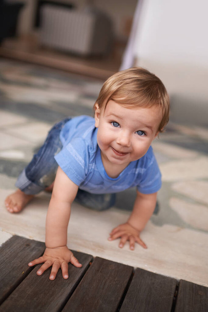 Floor, crawl and portrait of baby in home for fun playing, happiness and learning alone on ground. Relax, boy and face of a toddler with smile for child development, wellness or growth in a house. - Photo, Image