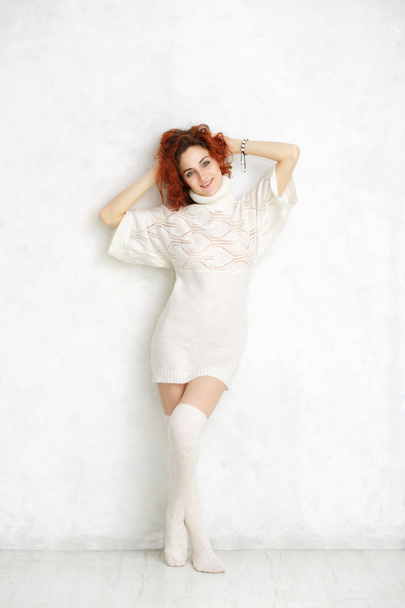 redhead curly girl in a white knitted sweater and stockings stan - Foto, Bild
