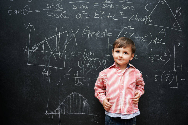 Kind, Junge und Gesicht mit Lächeln an der Tafel mit Gleichungen, Zahlen und Problemlösungen in der Schule. Kind, Student und glücklich für Wissen, Lernen und Kreidetafel mit Mathe und Vorschule. - Foto, Bild