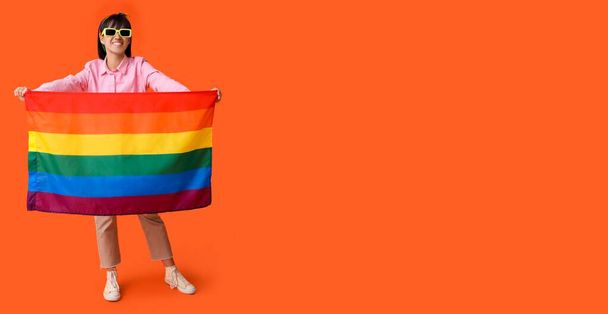 Piękna młoda kobieta z flagą LGBT na pomarańczowym tle z miejscem na tekst - Zdjęcie, obraz