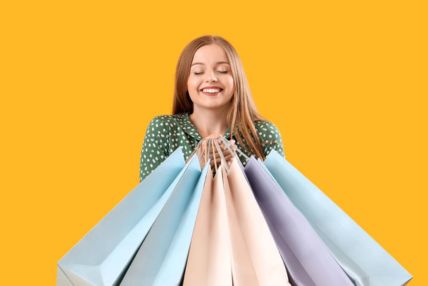 Pretty young woman with shopping bags on orange background - Photo, Image