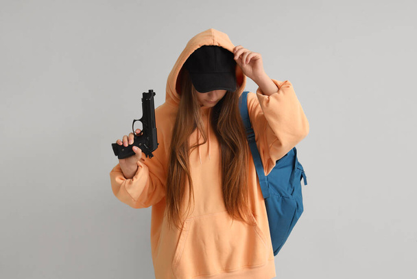 軽い壁の近くに銃を持った女子学生. スクールシューティングコンセプト - 写真・画像