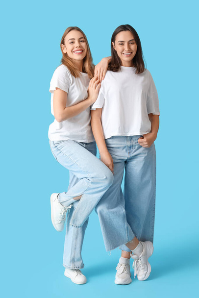 Young women in stylish jeans on blue background - Фото, изображение
