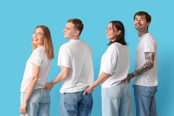 Группа молодых людей в стильных джинсах на синем фоне, вид сзади - Фото, изображение