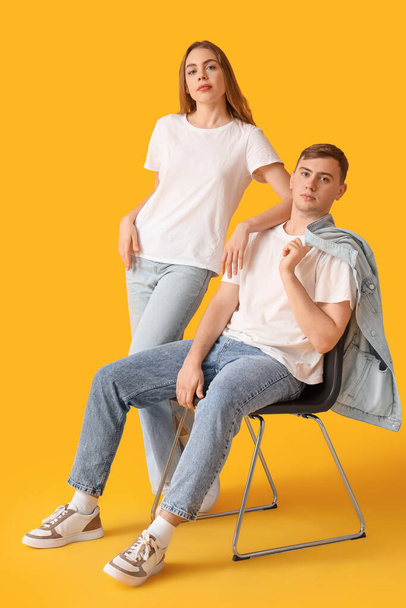 Молода пара в стильних джинсах на жовтому фоні - Фото, зображення