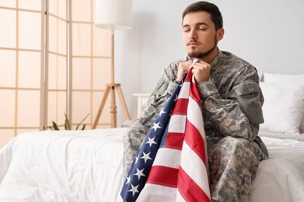 Молодой солдат с флагом США молится в спальне - Фото, изображение