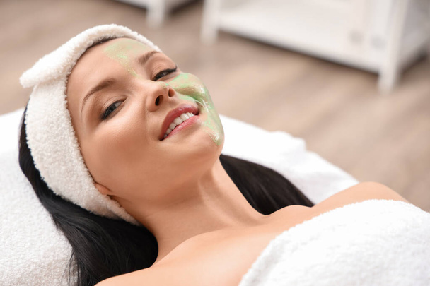 Beautiful woman with applied facial mask in beauty salon, closeup - Photo, Image