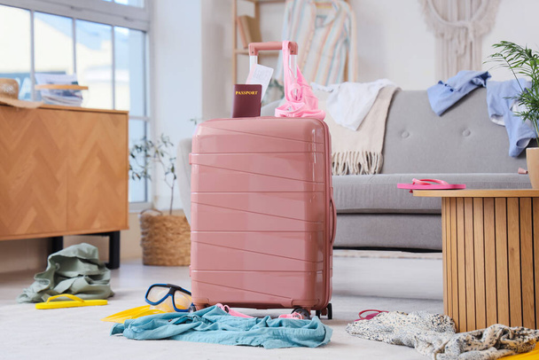 Розовый чемодан с паспортом в грязной гостиной - Фото, изображение
