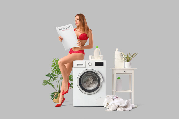 Atrakcyjna młoda kobieta w bieliźnie z gazetą robiąca pranie na jasnym tle - Zdjęcie, obraz