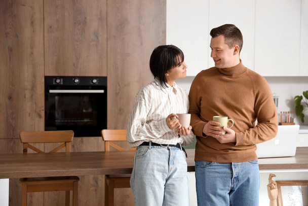 Jovem casal amoroso com xícaras de café na cozinha - Foto, Imagem