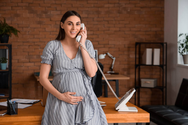 Embarazada mujer de negocios hablando por teléfono en la oficina - Foto, imagen