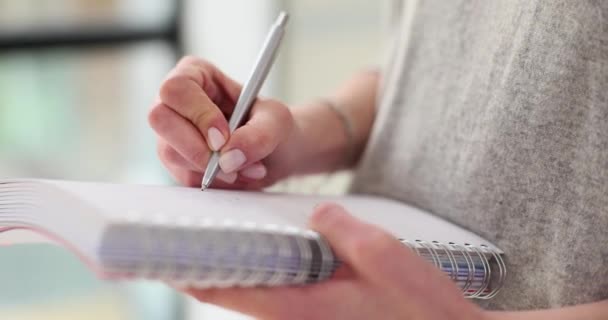 Vrouw vult pagina in notebook met gedachten en herinneringen in premise. Werknemer schrijft nauwgezet dagelijks schema met balpen in persoonlijke planner - Video