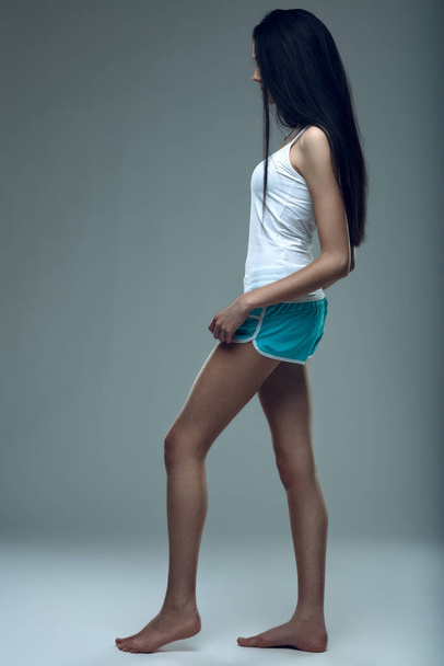 Атлетическая женщина стоит на ногах, демонстрируя силу и сосредоточенность. - Фото, изображение