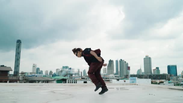 B-boy występ taneczny przez profesjonalnego ulicznego tancerza na dachu z scrapper niebo, widok na miasto. Atrakcyjny azjatycki hipster, poruszający się energicznym krokiem. Sport na świeżym powietrzu 2024. Styl hip-hopu. hiphop. - Materiał filmowy, wideo