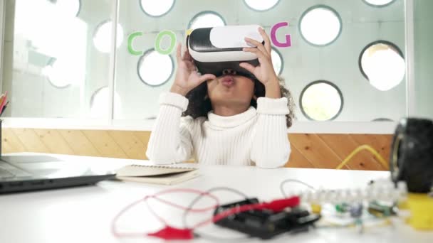 Meta evreni ziyaret etmek için heyecanlıyken VR görüş gözlüğü takan Afrikalı bir kız. Öğrenci görsel gerçeklik üzerine çalışıyor ve önünde el ele tutuşuyor. BTMM sınıf eğitiminde teknolojiyi kullanan bir çocuk. Etkinlik. - Video, Çekim