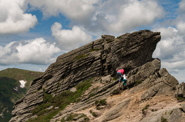 Moeder en dochter worden hoog beklommen op een rots gelegen op de berg Ukhaty Kamin, een oorsteen in de Karpaten. - Foto, afbeelding