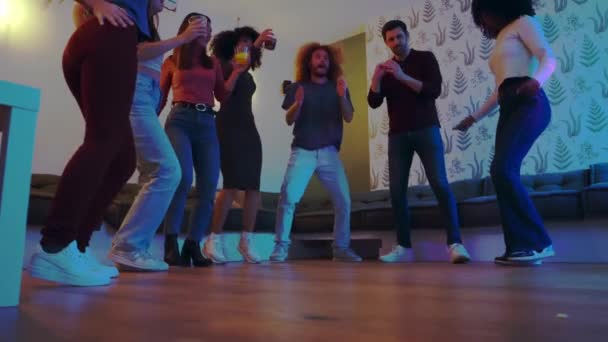 Smějící se přátelé si užívají párty s zrzkou muž předvádí breakdance tah na podlaze.  - Záběry, video