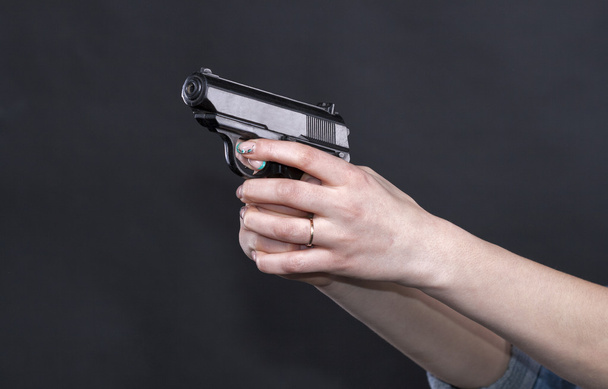 Καυκάσιες γυναίκες όπλων που κατέχουν ένα όπλο ενάντια σε μαύρο φόντο - Φωτογραφία, εικόνα
