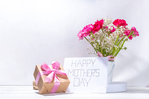 Anneler günü tebrik kartı, davetiye arkaplanı, güzel ranunculus çiçeği buketi, sevimli el işi kağıt hediye paketi ve not: Mutlu anneler günleri, beyaz arkaplanda kopyalama alanı - Fotoğraf, Görsel