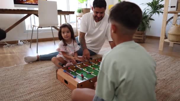 Familia alegre se involucra en un juego lúdico de fútbol en una acogedora sala de estar. - Imágenes, Vídeo