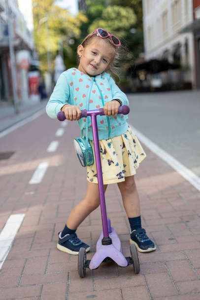 Feliz niña jugando con su scooter al aire libre  - Foto, Imagen