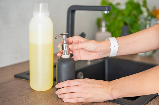 Uma mulher planeja derramar sabão ou detergente de embalagens recicladas em uma garrafa reutilizável. Conceito de estilo de vida ecológico. Foto de alta qualidade - Foto, Imagem